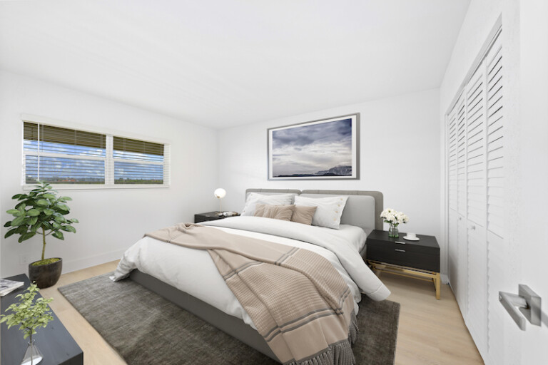 Modern minimalist bedroom with white walls, a grey upholstered bed, black nightstands, and a large window providing natural light.